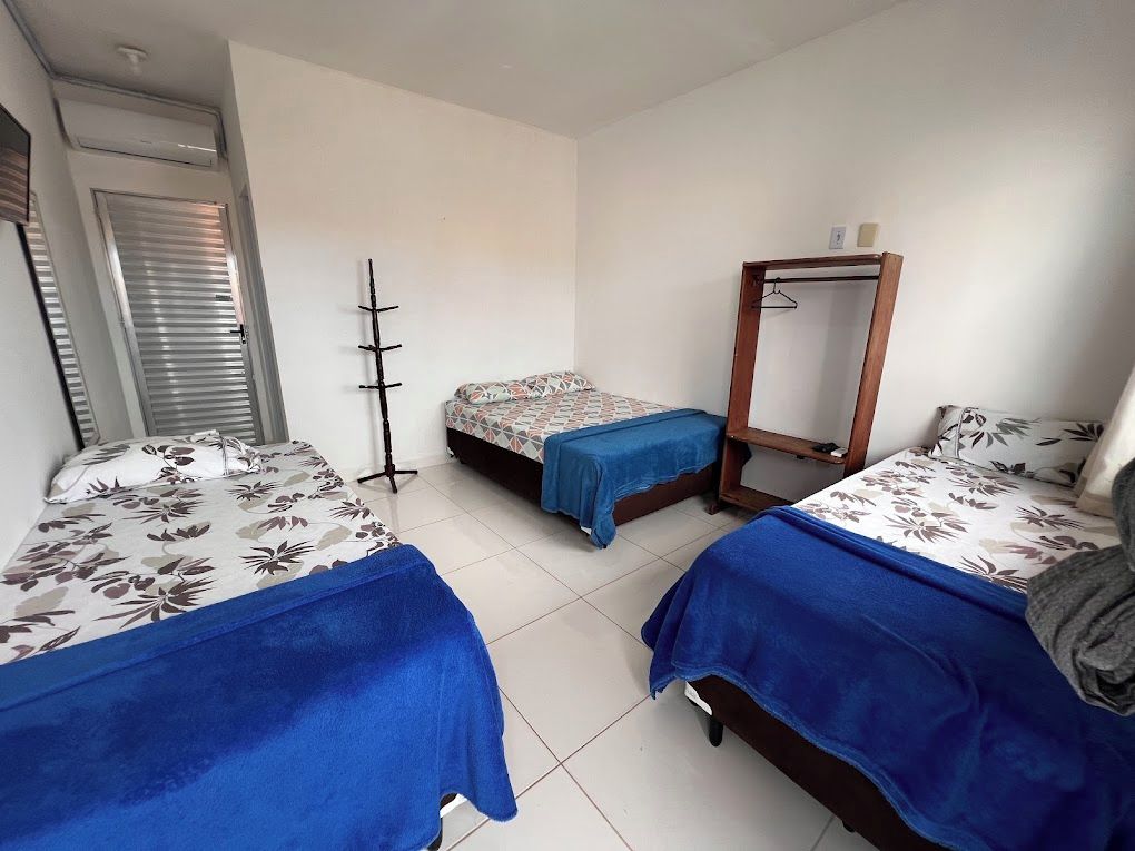 A room with two beds, a wardrobe, and a mirror.