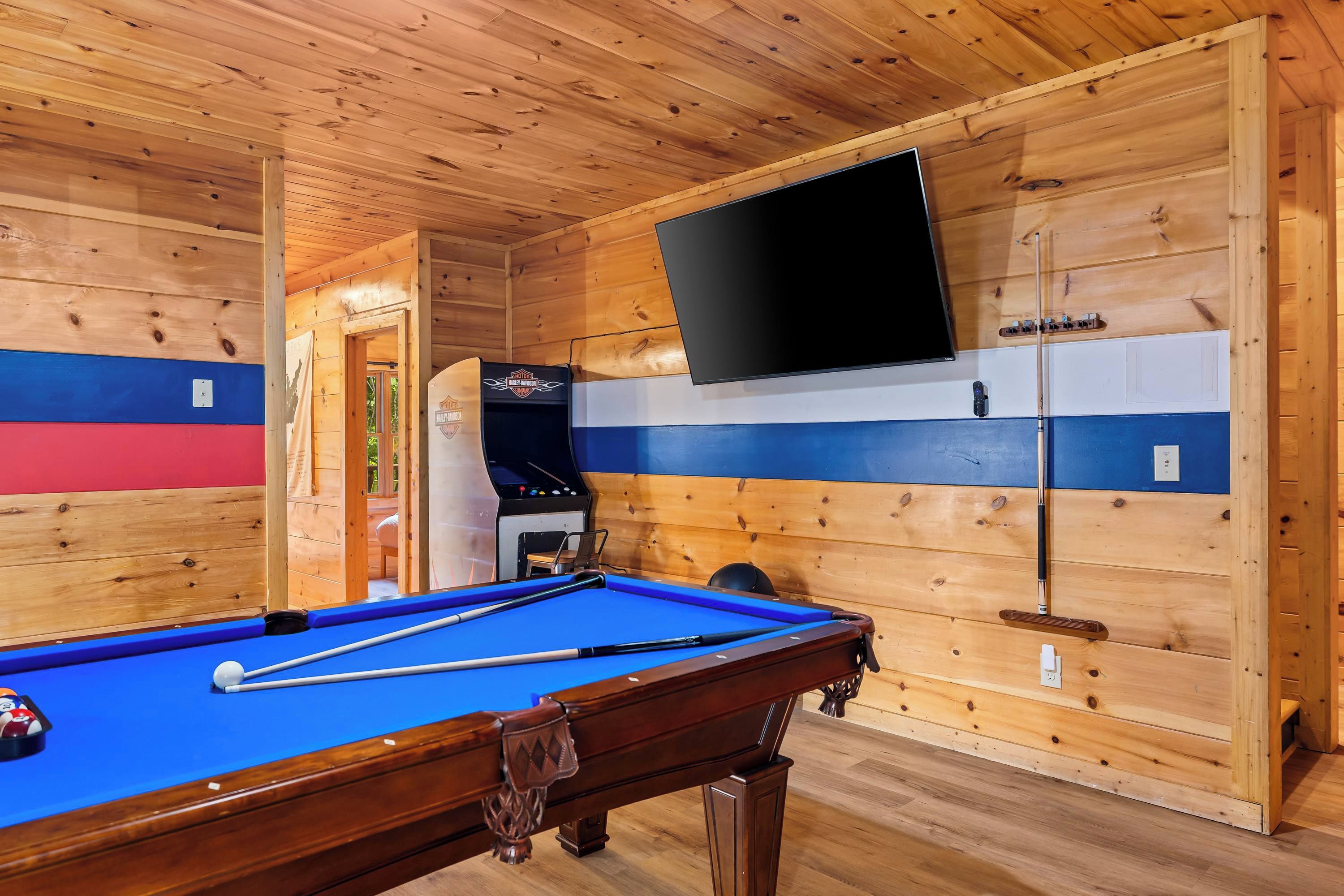 Une table de billard recouverte d’un drap bleu, un queue de billard et un jeu de billes.