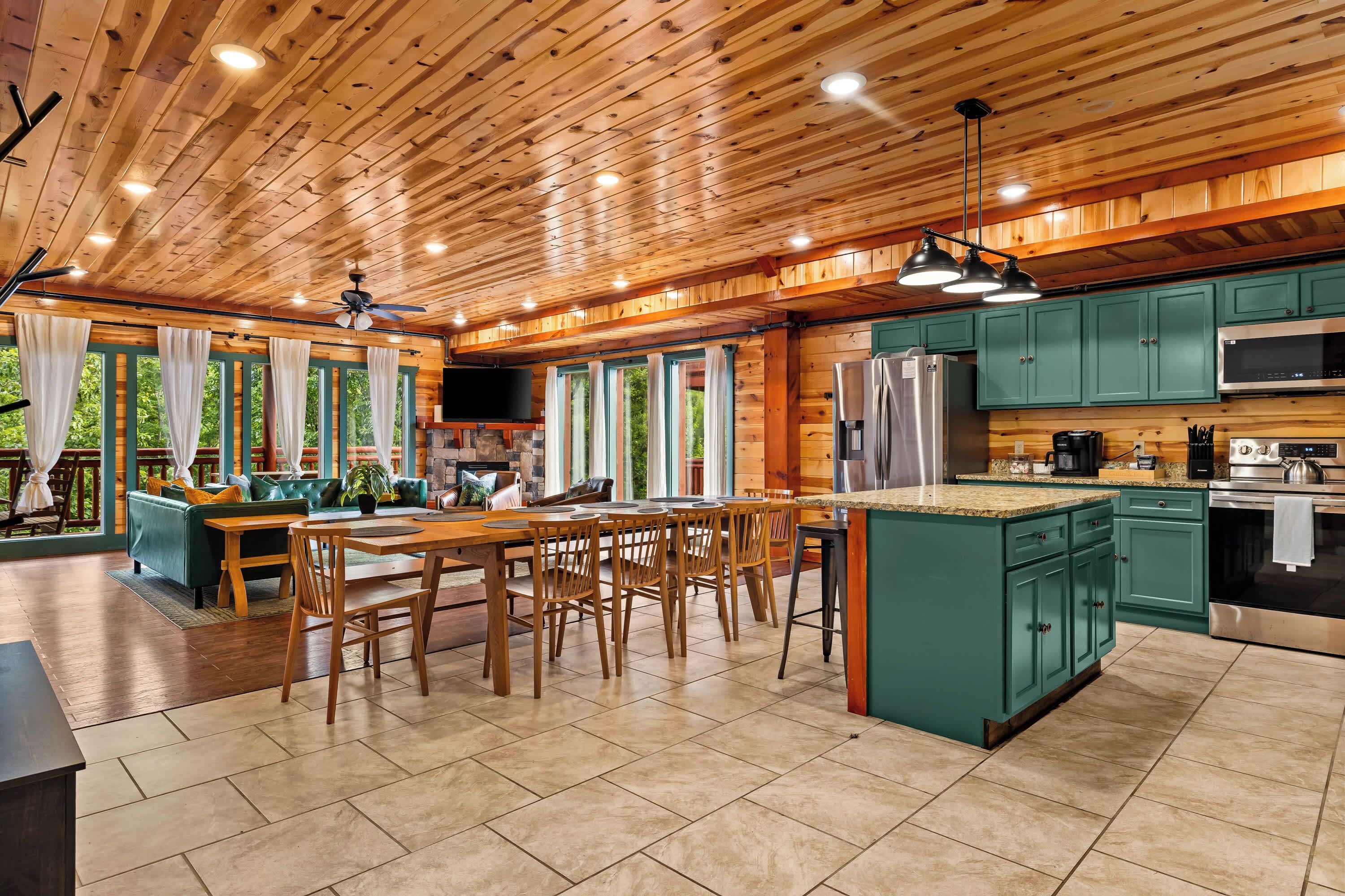 A spacious kitchen with a central island, wooden ceiling, and green cabinets.