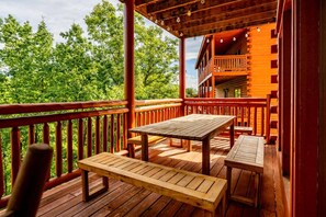 Gather around the picnic table on the covered rear deck for meals in the fresh mountain air. - 6BR Smoky Mountain Cabin | Private Indoor Pool, Hot Tub, Theater & 6 Ensuite Baths (Sevierville)