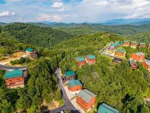 A resort with multiple buildings, roads, and dense forested hills in the background. - 6BR Smoky Mountain Cabin | Private Indoor Pool, Hot Tub, Theater & 6 Ensuite Baths (Sevierville)