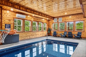 An indoor swimming pool with wooden walls and windows, a basketball hoop, and lounge chairs. - 6 Ensuite Bedrooms | Private Indoor Heated Pool, Theater, Hot Tub & Mountain Views (Sevierville)