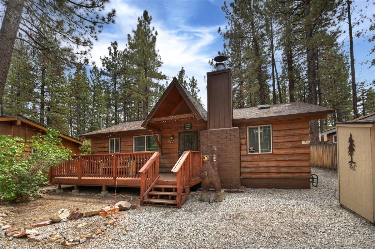 Une cabane dotée d’une terrasse en bois, d’une cheminée et d’un foyer en pierre.