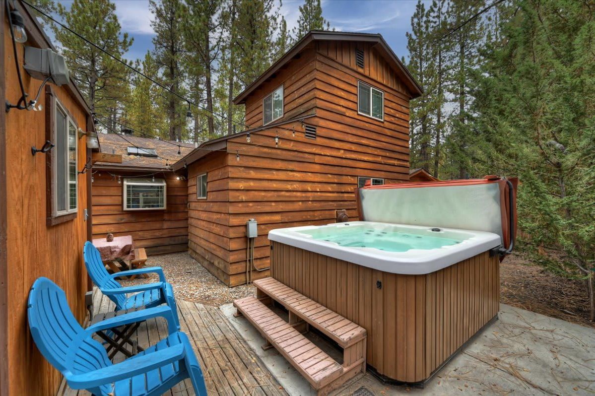 A wooden cabin with a hot tub and blue chairs.