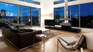 A modern living room with a sofa, a TV, a fireplace, and large windows. - Interlude, sleek modern retreat with hot tub (Daylesford)