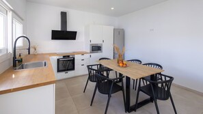 Een moderne keuken met een houten aanrecht, zwarte stoelen en een eettafel.
