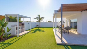 A rooftop patio with artificial grass, a pergola, a dining area with chairs and a table, and a small garden with a palm tree. - Casa Maricarmen Conil de la Frontera by Ruralidays (Cádiz)