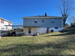 A residential house with a covered patio, a chimney, and a lawn. - Home Workplace/Getaway (Florence)