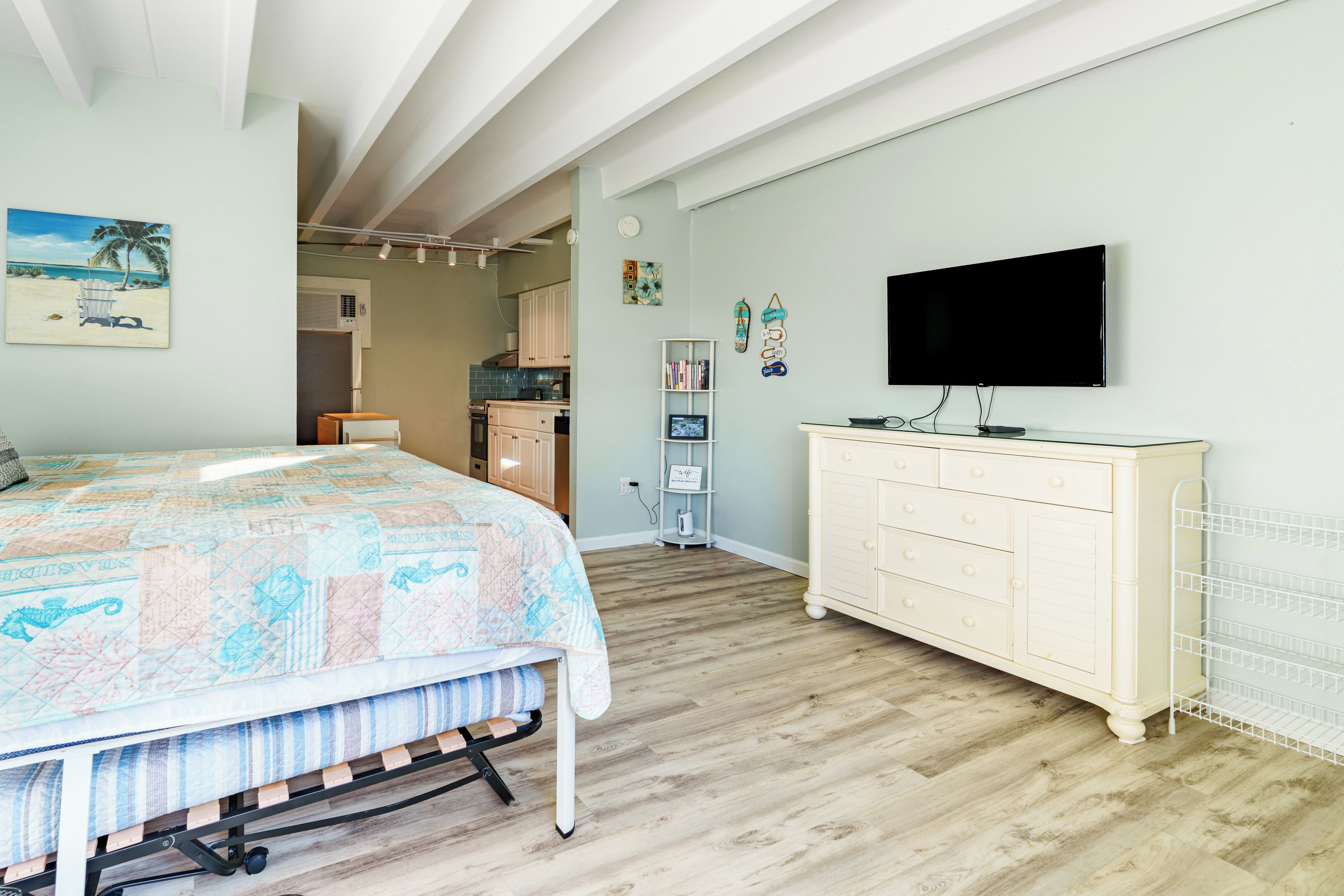 Een slaapkamer met een bed, een televisie, een dressoir en een kitchenette.