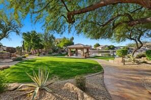 A well-maintained garden with a gazebo, a clear sky, and a view of houses in the background. - Staycation Home in Arizona|  Pool w/ BBQ (Glendale)