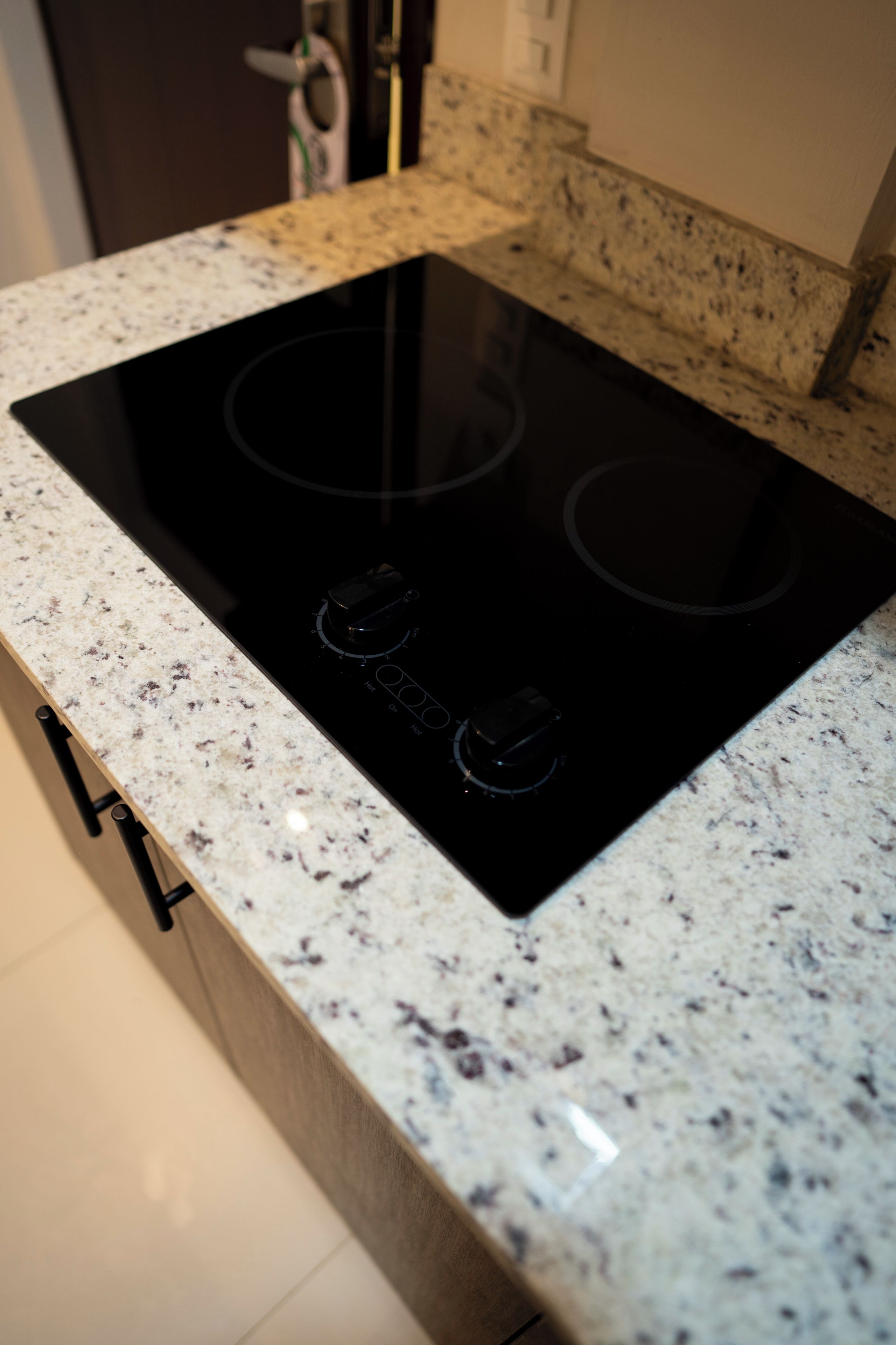 Una cocina con tope de inducción negro sobre encimera de granito moteado.