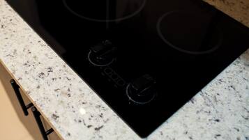 Una cocina con tope de inducción negro sobre encimera de granito moteado.
