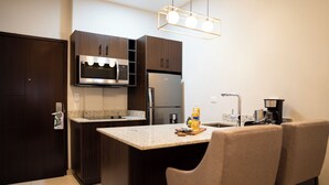 Una cocina moderna con gabinetes de madera oscura, electrodomésticos de acero inoxidable, una encimera de granito y una zona de bar con dos sillas.