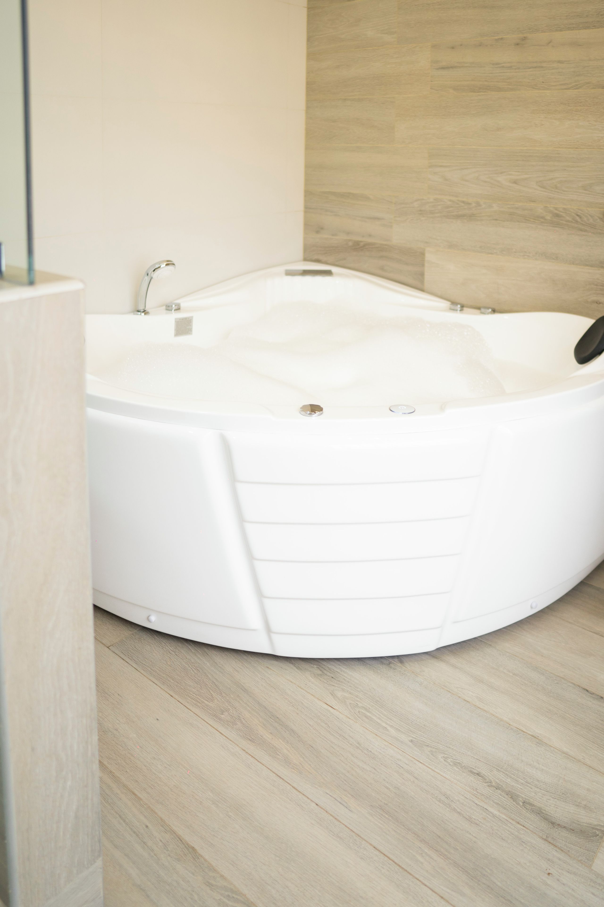 A modern bathroom with a freestanding bathtub, a shower, and a wooden floor.