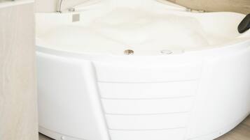 A modern bathroom with a freestanding bathtub, a shower, and a wooden floor.