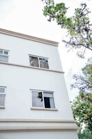 Un edificio de varios pisos con paredes exteriores blancas y numerosas ventanas.