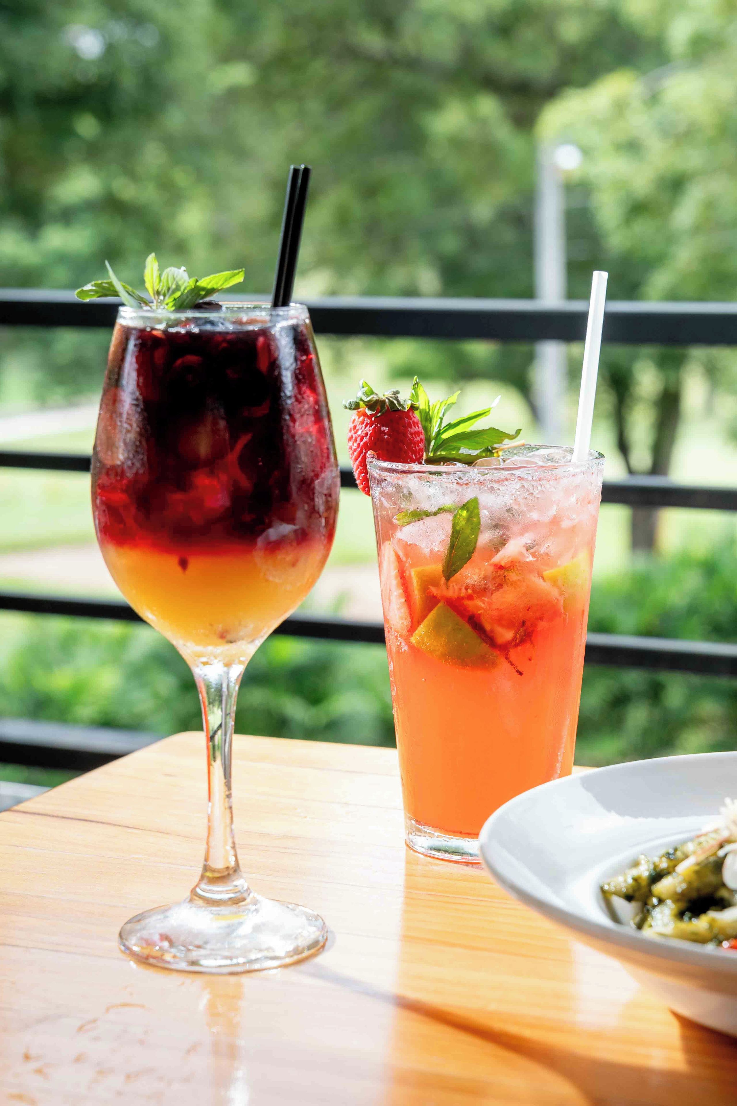 Dos bebidas sobre una mesa con vistas a la vegetación.