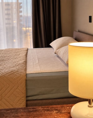 Une chambre d’hôtel avec un lit, une lampe de chevet et une vue sur les bâtiments par la fenêtre.