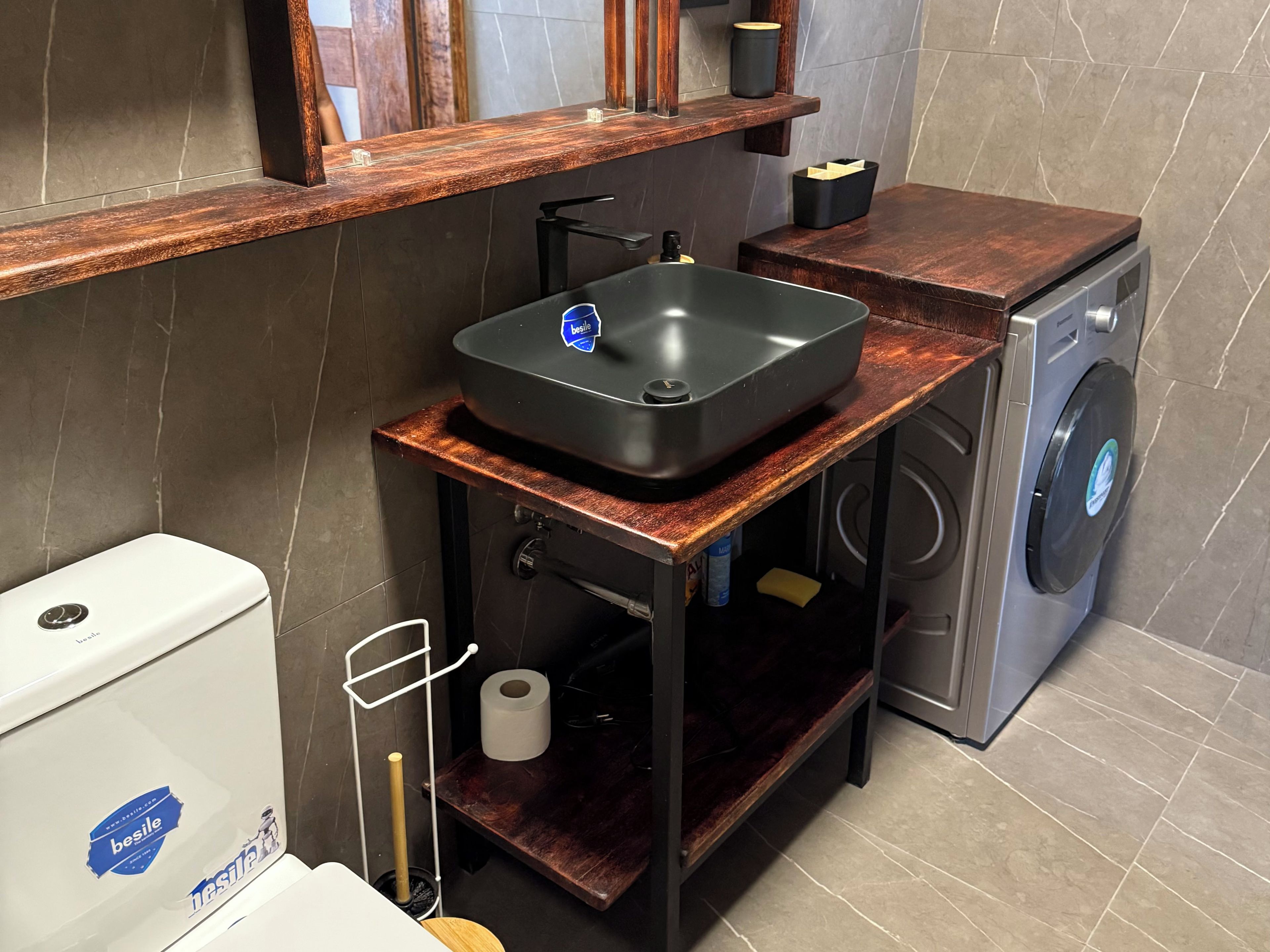 Casa de banho compacta com lavatório, sanita e máquina de lavar roupa.
