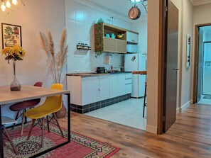 Une cuisine moderne avec des meubles blancs, un plan de travail en bois et un coin repas comprenant une table et des chaises.