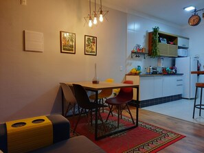 A dining area with a table, chairs, and a red patterned rug. - Charme e Conforto em Campos: 1º Andar, Elevador e Vaga (Campos do Jordão)