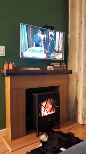 A television mounted above a wooden mantelpiece with a fireplace below. - Charme e Conforto em Campos: 1º Andar, Elevador e Vaga (Campos do Jordão)