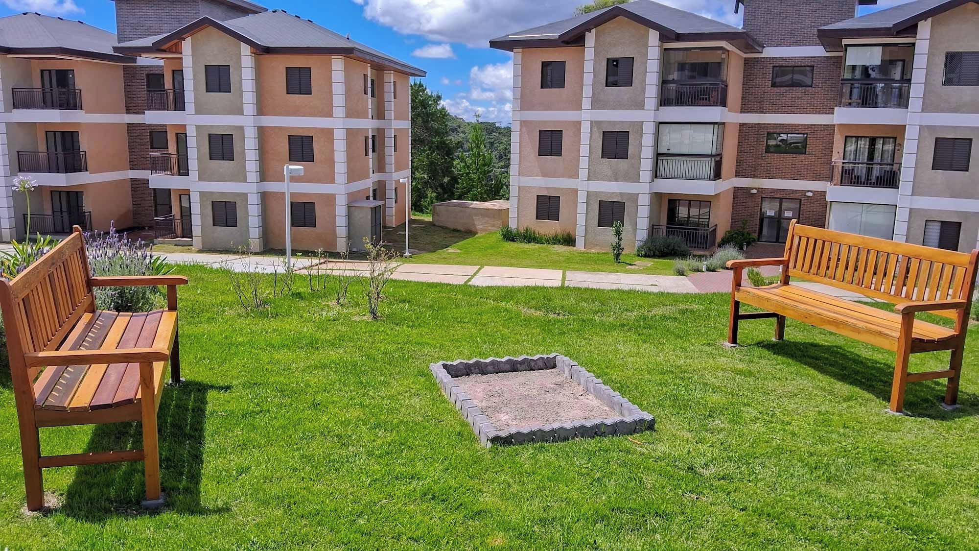 A courtyard with two wooden benches, a small fire pit, and a well-maintained lawn.