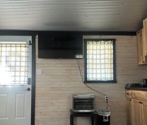 A kitchen with a built-in oven, a window with a grid pattern, and wooden cabinets. - Adorable 1-bedroom cabin with AC out in the country (Russellville)