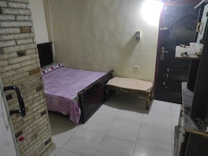 Una habitación con cama, un banco, una mesita y un armario.