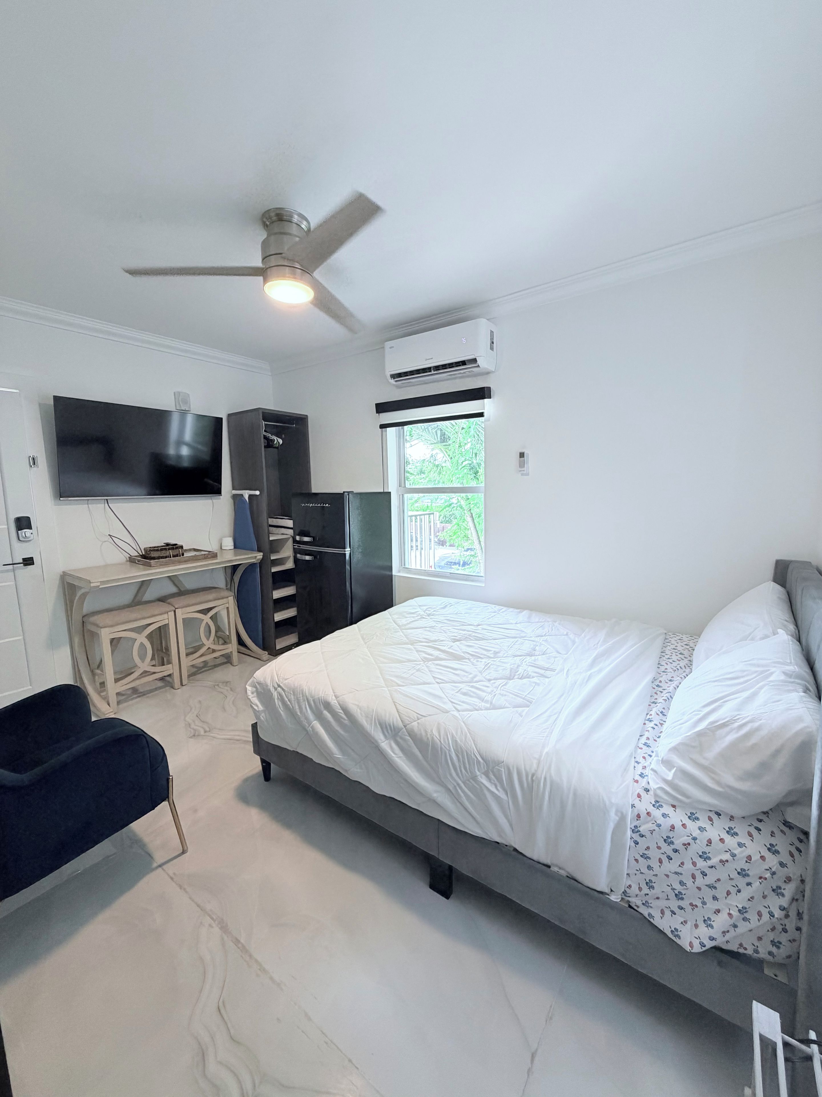 Une chambre à coucher comprenant un lit, un bureau, une chaise, un téléviseur et un appareil de climatisation.