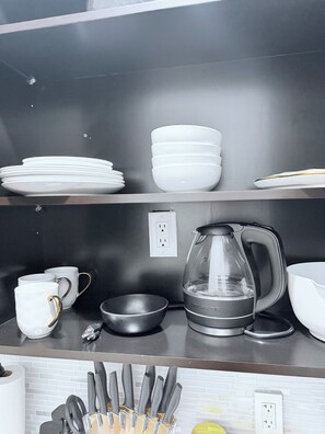 A kitchen counter with white plates, bowls, a coffee maker, and a knife block. - Cozy studio apartment in tranquil Tavernier with AC and kitchen. (Tavernier)
