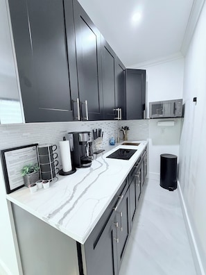 A modern kitchen with dark cabinets, a white countertop, and a microwave. - Cozy studio apartment in tranquil Tavernier with AC and kitchen. (Tavernier)