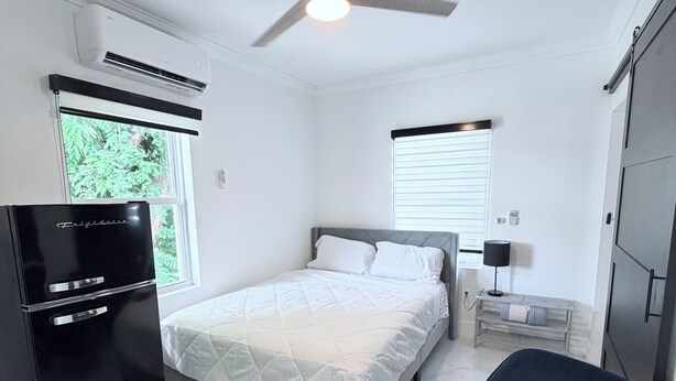 A bedroom with a bed, a chair, a wardrobe, a ceiling fan, and a window. - Cozy studio apartment in tranquil Tavernier with AC and kitchen. (Tavernier)