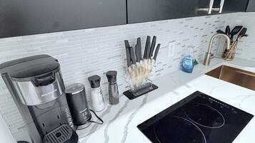 Eine Küche mit Kaffeemaschine, Salz- und Pfefferstreuern, einem Messerblock und einer schwarzen Induktionskochplatte.