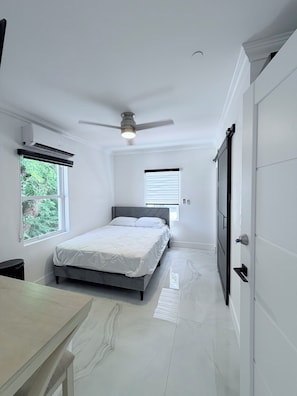 A bedroom with a bed, ceiling fan, and a window. - Cozy studio apartment in tranquil Tavernier with AC and kitchen. (Tavernier)