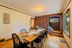 A dining area with a brick wall, wooden table, and chairs. - Storybook Upper Suite | Pool, Hot Tub, BBQ Grill (Seattle)
