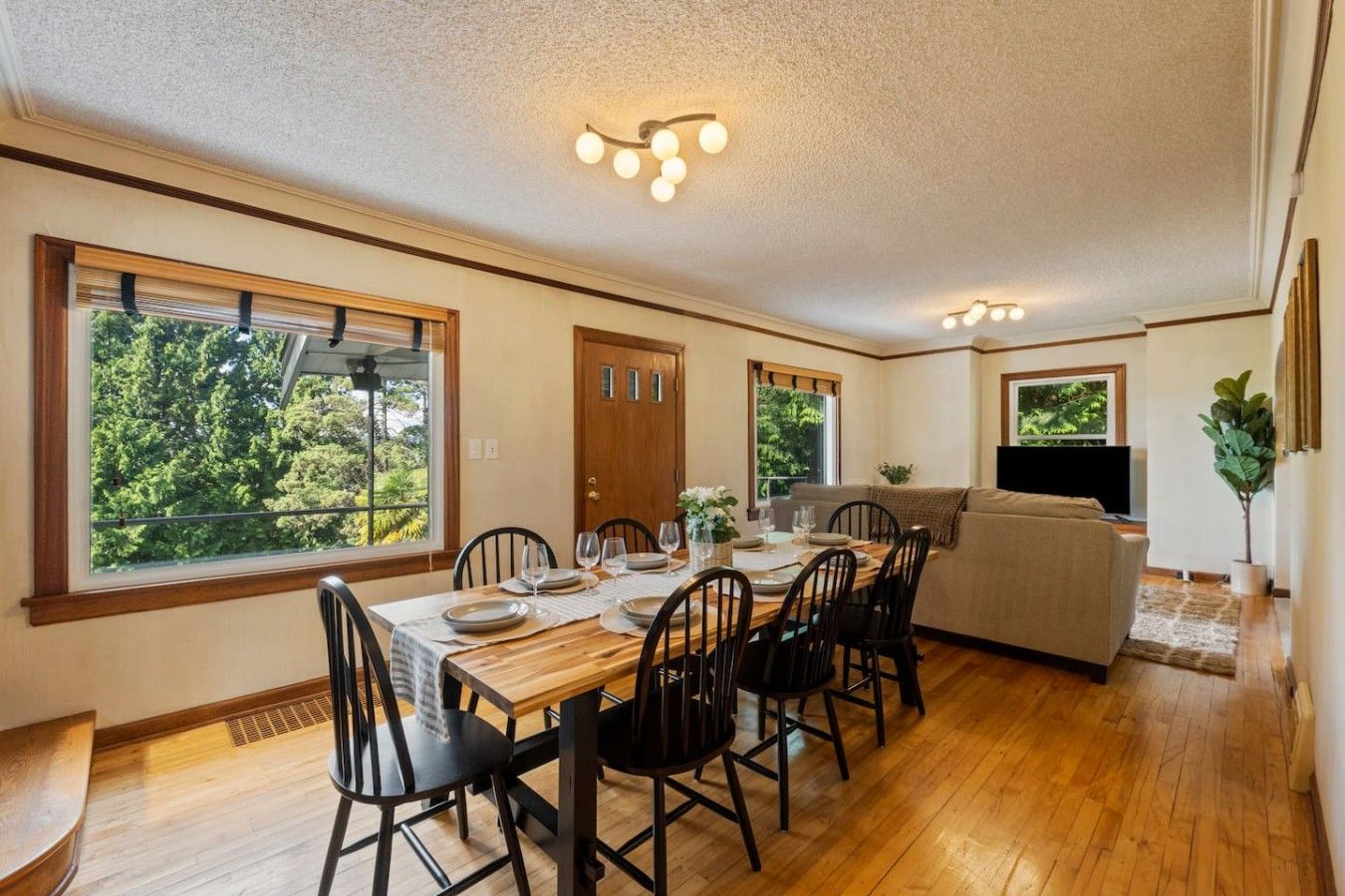 A dining area with a wooden table and chairs, a sofa, and a television in a living area.