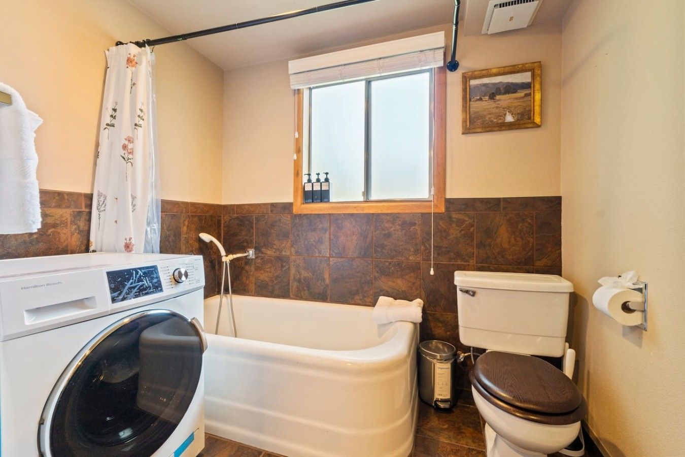 Une salle de bain équipée d’un lave-linge, d’une baignoire, de toilettes et d’une fenêtre donnant sur un beau paysage.