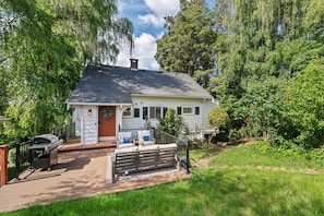 A single-story house with a porch, a grill, and a small garden.