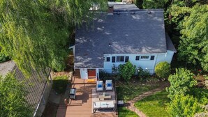 A single-story house with a deck, surrounded by trees. - Cozy Garden Suite w/ Pool & Hot Tub | Near Airport (Seattle)