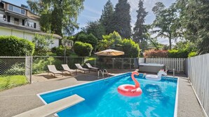 A swimming pool with lounge chairs and inflatable flamingos. - Cozy Garden Suite w/ Pool & Hot Tub | Near Airport (Seattle)
