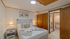A bedroom with a bed, two bedside tables, a wooden wardrobe, and a door leading to another room. - Cozy Garden Suite w/ Pool & Hot Tub | Near Airport (Seattle)