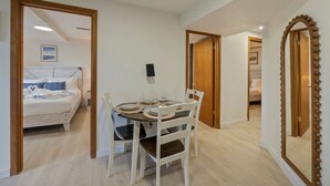 A room with a dining table set for four, a bed with a blue and white duvet, and a large mirror with a decorative frame. - Cozy Garden Suite w/ Pool & Hot Tub | Near Airport (Seattle)