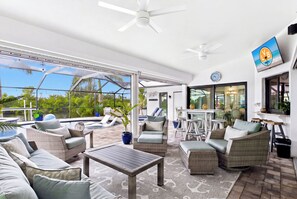Área de lounge ao ar livre com bancos, piscina e bar.