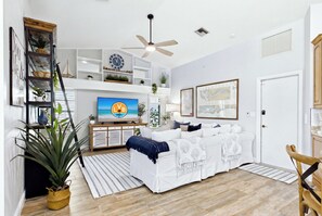 A modern living room with a sofa, TV, ceiling fan, and various decorative items. - Southbound Haven (Cape Coral)