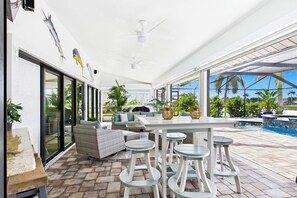 Área de varanda externa com piscina, assentos e ventilador de teto.