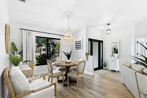 Uma sala de jantar com uma mesa de madeira posta para quatro pessoas, rodeada por cadeiras estofadas.