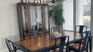 Un comedor con una gran mesa de madera, seis sillas, un aparador de madera oscura y una planta en maceta.