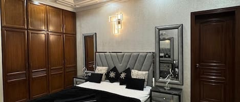 A bedroom with a bed, bedside tables, a ceiling fan, wardrobe, and a mirror.