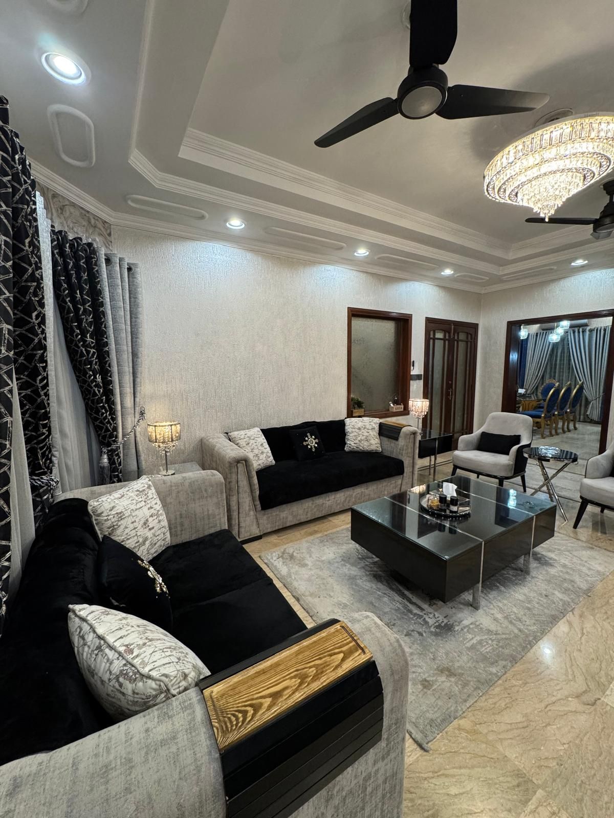 Un salon moderne doté d’un ventilateur de plafond, d’un lustre et d’un grand miroir.